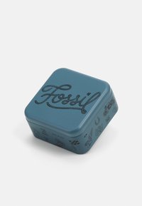Neliömäinen sininen metallikotelo, jossa on musta köysimäinen "Fossil"-logo ja erilaisia kuvastoikoneita sivuilla. Sujuva pinta, kiiltävä viimeistely.