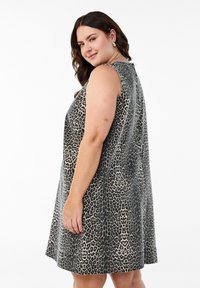Mouwloze jurk met luipaardprint van zacht materiaal, met een losse pasvorm, ronde halslijn en een knie-lange zoom. Kleurenpalet: zwart en beige.