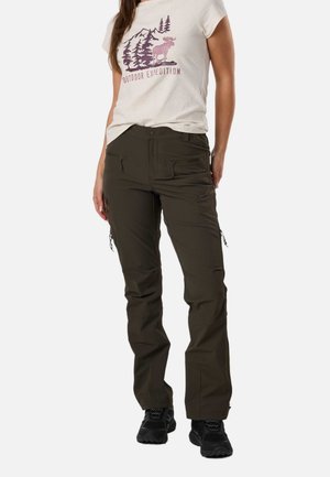 Frau trägt ein beiges "Outdoor Expedition" T-Shirt mit Baum- und Elch-Grafik, dunkelgrüne Cargohose und schwarze Wanderschuhe.