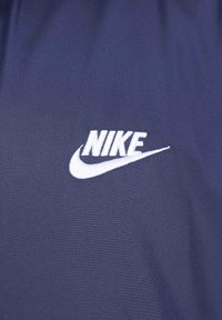 Marinblå idrottströja med en mjuk textur och en vit broderad Nike-logga på vänster sida. Enkel och ren design.