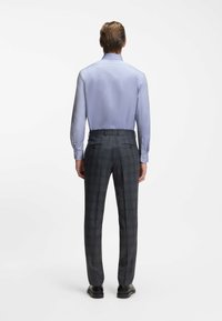 Lichtblauw overhemd met lange mouwen van een soepele stof, gecombineerd met donkergrijze geruite broek met rechte pijpen en twee achterzakken.