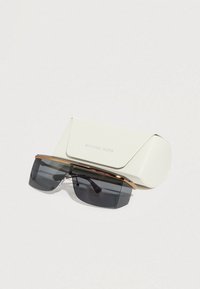 Γυαλιά ηλίου με σκουρόχρωμους γκρι φακούς, χρυσή λεπτομέρεια στο πάνω μέρος και κομψό μαύρο πλαίσιο. Συνοδεύονται από λευκή υφασμάτινη θήκη με την ετικέτα «Michael Kors».