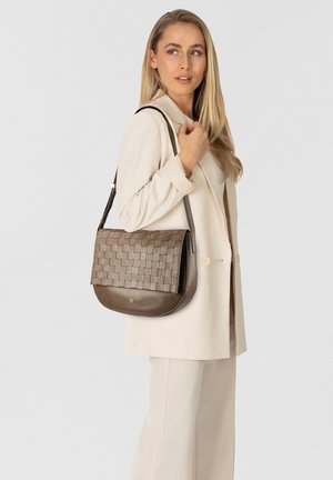 Borsa a tracolla in pelle intrecciata marrone con base liscia, dotata di una chiusura a patta piatta e una lunga tracolla regolabile, che completa un outfit neutro.