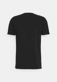 T-shirt noir uni manches courtes, vu de dos sur un fond gris clair.