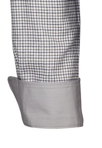 Cuff grigio di una camicia a quadri con un motivo a griglia bianca e marrone, che mette in evidenza una texture del tessuto liscia e un design strutturato.