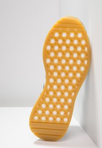 Gummiskosula i orange med ett bikake-mönster och vita accenter, med Adidas-logotypen. Ren och strömlinjeformad design.