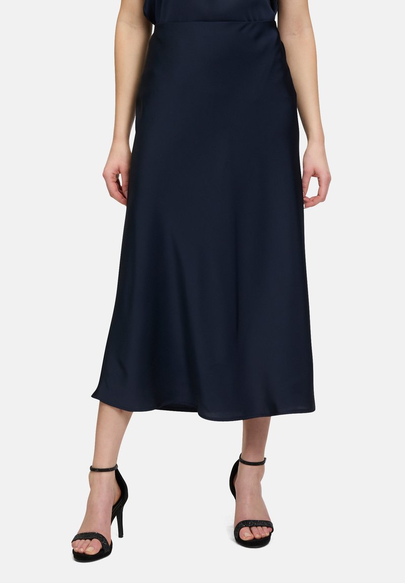 Navy satin midi skirt with a smooth texture, A-line shape, and subtle flare at the hem, paired with black strappy high-heeled sandals.