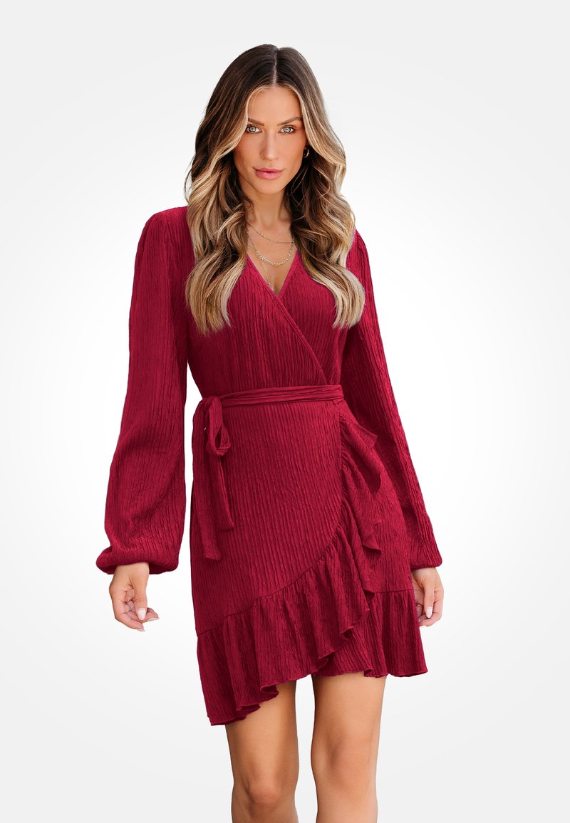 Rotes, geripptes Wickelkleid mit langen Ärmeln, einem Rüschensaum und einem Bindegürtel. Es verfügt über einen tiefen V-Ausschnitt und eine strukturierte Stoffoberfläche.