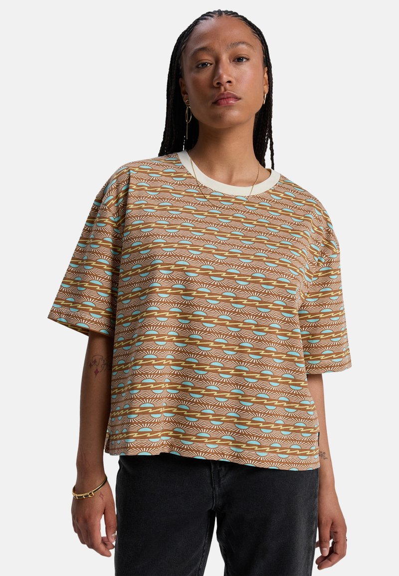 Καφέ φαρδιά μπλούζα με γεωμετρικά σχέδια σε τιρκουάζ και λευκό. Κοντά μανίκια, στρογγυλή λαιμόκοψη, απαλό ύφασμα, άνετη εφαρμογή.