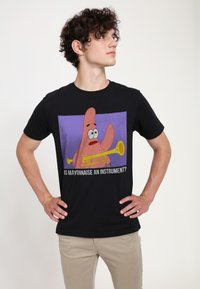 Black cotton t-shirt featuring a graphic of a pink character playing a yellow trumpet, with purple background and text "IS MAYONNAISE AN INSTRUMENT?"