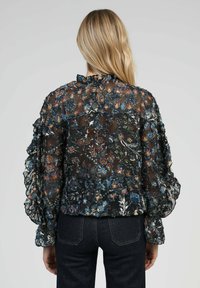 Blouse noire à fleurs avec des manches froncées, en tissu transparent, motifs floraux multicolores, et fermeture à boutons au dos.