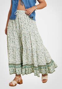 Lennokas, kerroksittain oleva maksihame vaaleassa kukkakuviossa, jossa on vihreitä yksityiskohtia. Hameessa on joustava vyötärö ja röyhelöhelma. Yhdistetty ruskeisiin korkokenkiin.