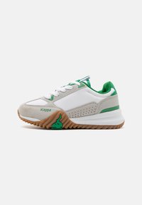 Zapatilla blanca con acentos verdes, materiales de ante y malla, puntera redonda, suela de goma texturizada y marca en el lateral y el talón.