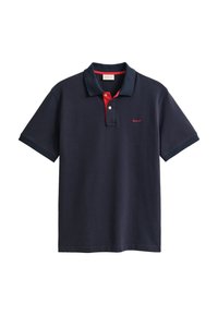 Polo bleu marine à manches courtes avec patte intérieure rouge et petit logo rouge GANT sur la poitrine gauche.