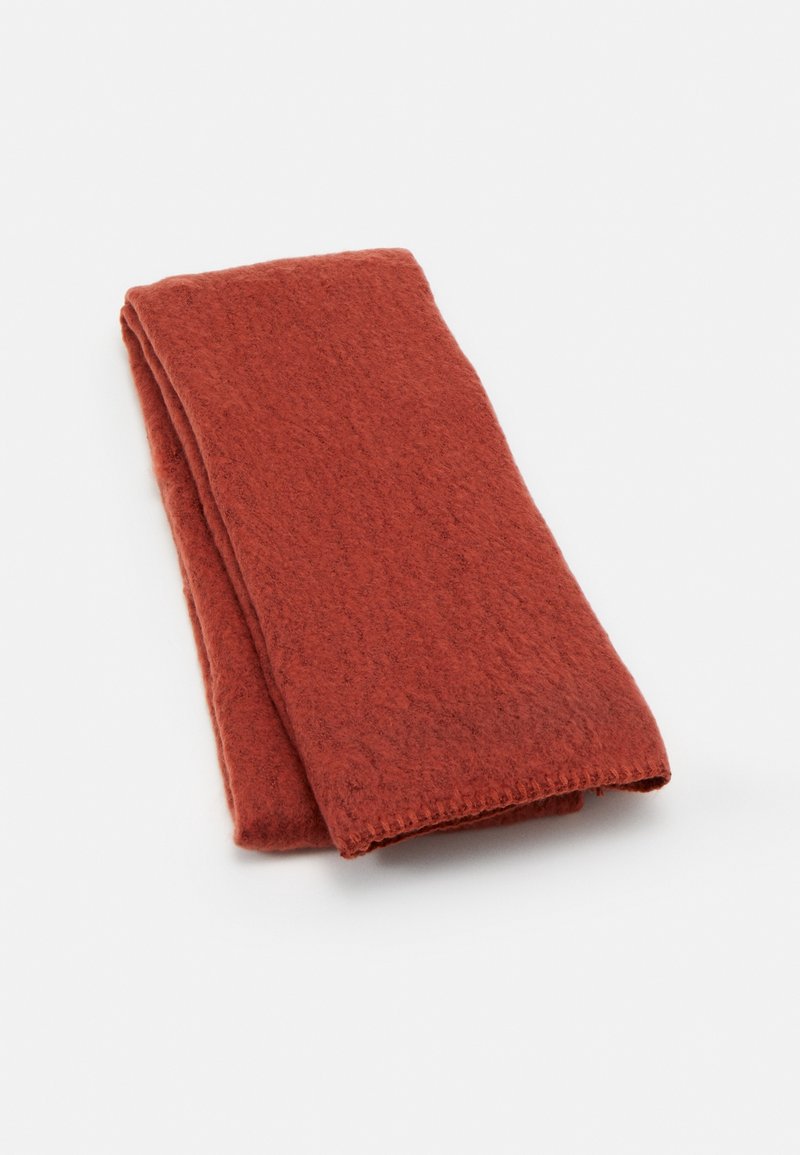 Écharpe en laine pliée de couleur rouille avec un tissu doux et texturé, présentée sur un fond blanc.