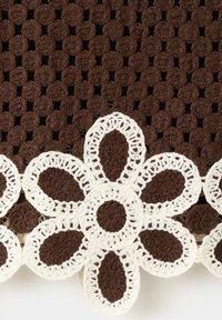 Tissu marron crocheté avec un motif de fleurs blanches crochetées le long du bord, chaque fleur a six pétales et un centre circulaire.