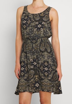 Mouwloze jurk met zwart, olijfgroen en beige bloemen- en paisleypatroon, elastische taille, gedragen door een persoon die tegen een effen achtergrond staat.