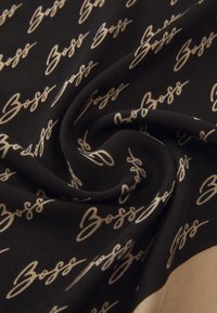 Black fabric featuring a repeating pattern of the word "Boss" in gold script. Smooth texture with a soft, flowing drape.