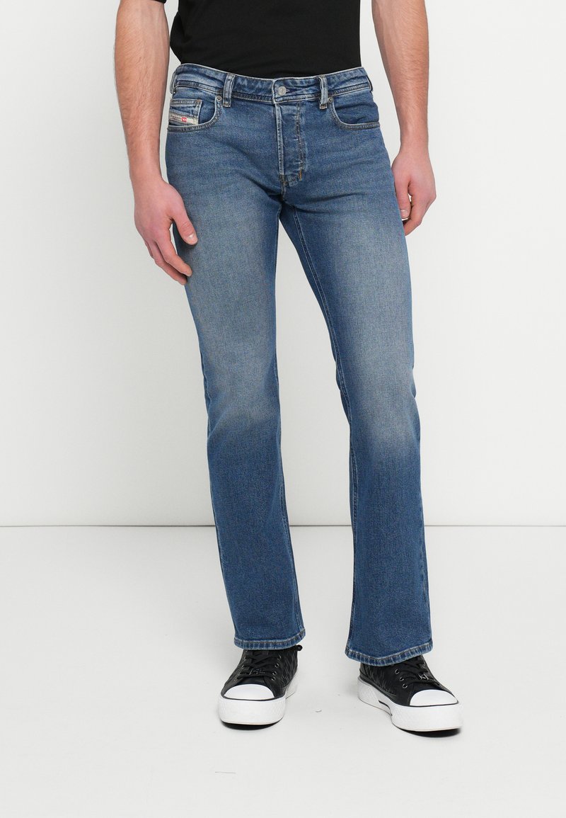 Sinised teksad, sirge säärega, heledate kulumisjälgedega, viie taskuga ja nööpidega sulguvad. Kandmisel mustad tossud, millel on valged tallad.