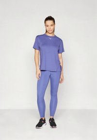 Lilla sportlik ülaosa lühikeste varrukate ja külgseintega ning sobivate lilla retuusidega. Varustuses on mustad spordijalatsid roosade detailidega.