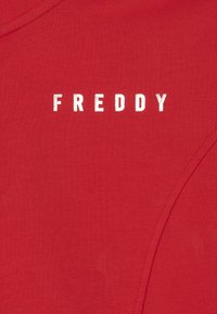 T-shirt in cotone rosso con scritta bianca ricamata "FREDDY." Texture liscia, con scollatura a girocollo e design semplice.