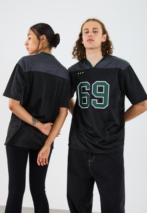 Black sports jersey with green accents, featuring the number 69 in large print. Made from breathable fabric, with short sleeves and a v-neck.