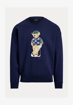 Φούτερ σε ναυτικό μπλε χρώμα με σχεδιασμό αρκούδας καρτούν ντυμένης με γκολφ, φορώντας πουλόβερ με αργκολέ μοτίβο και κλασικό παντελόνι. Με ribbed μανσέτες και τελείωμα.