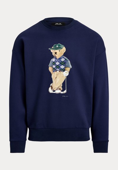 Φούτερ σε ναυτικό μπλε χρώμα με σχεδιασμό αρκούδας καρτούν ντυμένης με γκολφ, φορώντας πουλόβερ με αργκολέ μοτίβο και κλασικό παντελόνι. Με ribbed μανσέτες και τελείωμα.