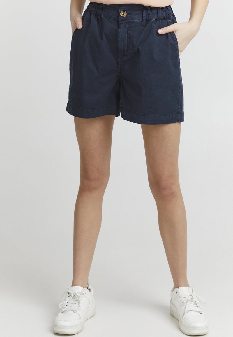Pantalones cortos de algodón azul marino con un corte relajado, cintura elástica y cierre de botón. Presenta bolsillos laterales y dobladillo doblado.