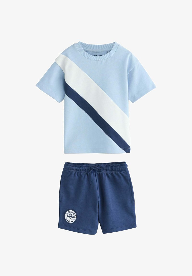 Chemise bleu clair à manches courtes avec des rayures diagonales blanches et bleu marine, associée à un short à taille élastique bleu marine orné d'un écusson rond.