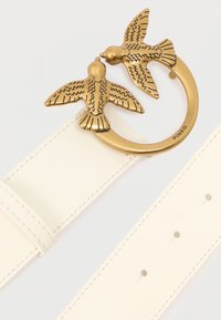 Biały skórzany pasek z klamrą w kolorze złotym, zdobioną dwoma szczegółowo wykonanymi ptakami w locie oraz wygrawerowaną nazwą marki "Pinko" na pierścieniu.