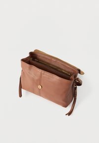 Καφέ δερμάτινη τσάντα χειρός με εσωτερική τσέπη με φερμουάρ, διακοσμητικό κουμπί και πλαινά φουντίτσες. Λείο υλικό με μινιμαλιστικό σχεδιασμό.