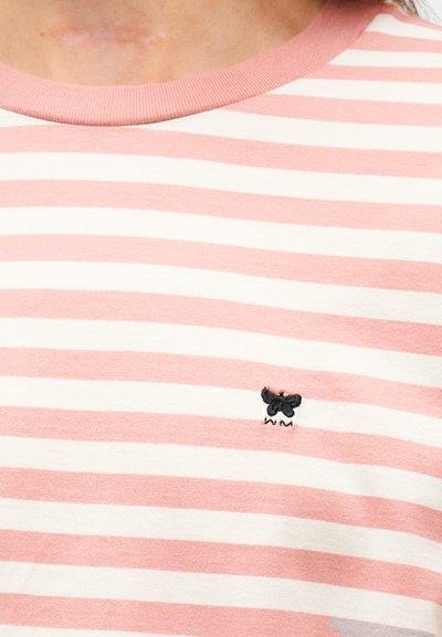 Κοντινή λήψη ροζ και λευκού ριγέ πουκάμισου με μικρή μαύρη κεντημένη πεταλούδα κοντά στην περιοχή του στήθους.