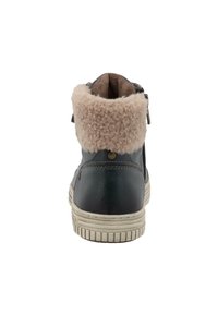 Černá kožená kotníková obuv s hebkým béžovým feldrovaným límcem, detaily na zipu a světle zbarvenou gumovou podrážkou s texturovaným vzorem.