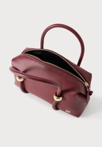 Sac à main en cuir bordeaux avec poignées arrondies, quincaillerie dorée et fermeture éclair ouverte révélant une doublure noire.