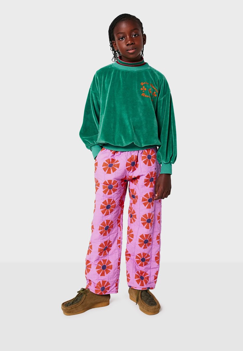 Sweatshirt en velours vert avec des manches ballons et des détails brodés, associé à un pantalon matelassé rose ornés de motifs floraux rouges avec des centres noirs.