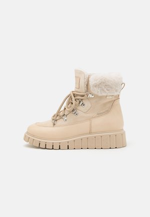 Bottines en cuir beige avec un col en fausse fourrure, bout rond, semelle en caoutchouc, œillets métalliques et lacets décoratifs. Accents texturés sur le dessus.