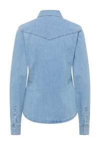 Camicia in denim azzurro chiaro a maniche lunghe con yoke appuntito sul retro, polsini abbottonati e cuciture sagomate per una silhouette adattata.