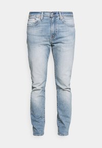 Jeans de denim azul claro con un corte ajustado, diseño de cinco bolsillos, un ligero desvanecimiento y cierre de botón. Presenta detalles de costura a lo largo de las costuras.