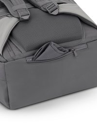 Gray backpack with padded mesh back, multiple straps, zippered front pocket, and textured fabric; minimalistic design and neutral color.