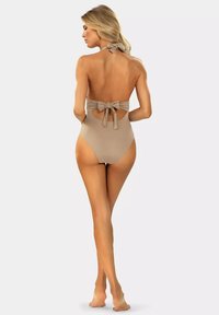Beżowy jednoczęściowy strój kąpielowy z dekoltem na szyi, marszczeniami i kokardą z tyłu; cechuje się wycięciem na dolnej części pleców.