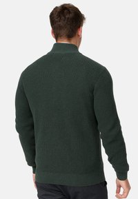 Suéter de punto verde oscuro con un cuello alto, puños acanalados y dobladillo. Patrón texturizado con un diseño ajustado, visto desde la parte posterior.