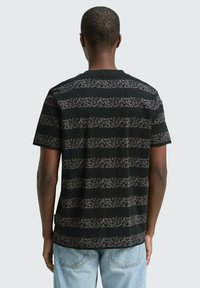 Zwarte t-shirt met horizontale strepen in een pixelpatroon in verschillende grijstinten. Korte mouwen en een ronde hals.