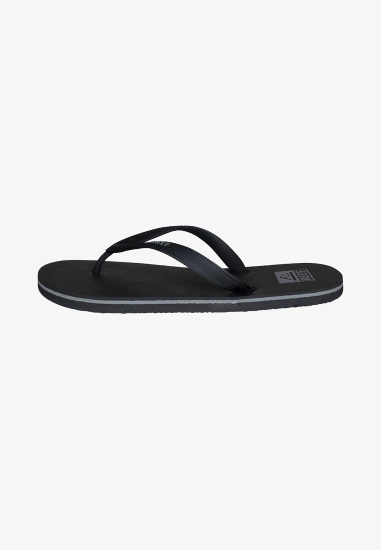 Tongs noires avec des brides texturées et une semelle en caoutchouc plate. Présentent une bande d'accent grise le long du bord et un logo sur la semelle intérieure.