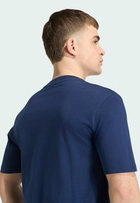 Marineblauw katoenen T-shirt met korte mouwen, ronde hals, gladde textuur en een aansluitend ontwerp, gezien vanuit de achterkant.