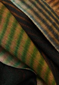 Tissu multicolore avec des motifs à rayures diagonales dans des teintes de vert, marron et noir. Tricot texturé avec une finition douce.