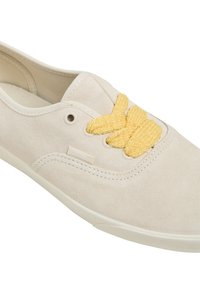 Beige suede sneaker with yellow braided laces, round toe, reinforced eyelets, and textured side detailing. Lightweight rubber sole.