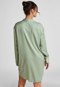 Robe chemise à manches longues, ample, en satin vert clair, avec un col pointu, des poignets boutonnés et un léger éclat, atteignant le milieu de la cuisse.