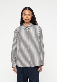 Camicia a righe grigia e bianca, realizzata in tessuto leggero. Dotata di colletto, maniche lunghe e tasca sul petto.