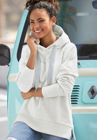 Light gray hoodie with drawstrings and ribbed cuffs, relaxed fit, features a logo on the chest, paired with light blue distressed jeans.